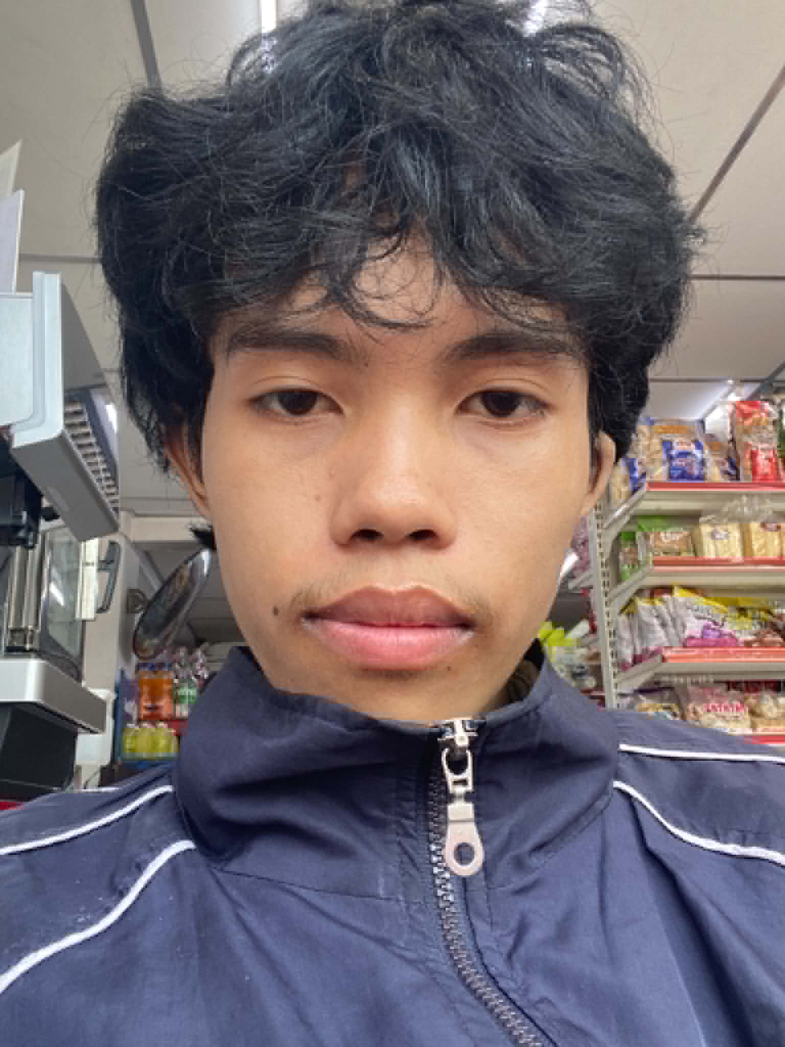 Jazdy taking a selfie in a store aisle, shelves stacked behind him