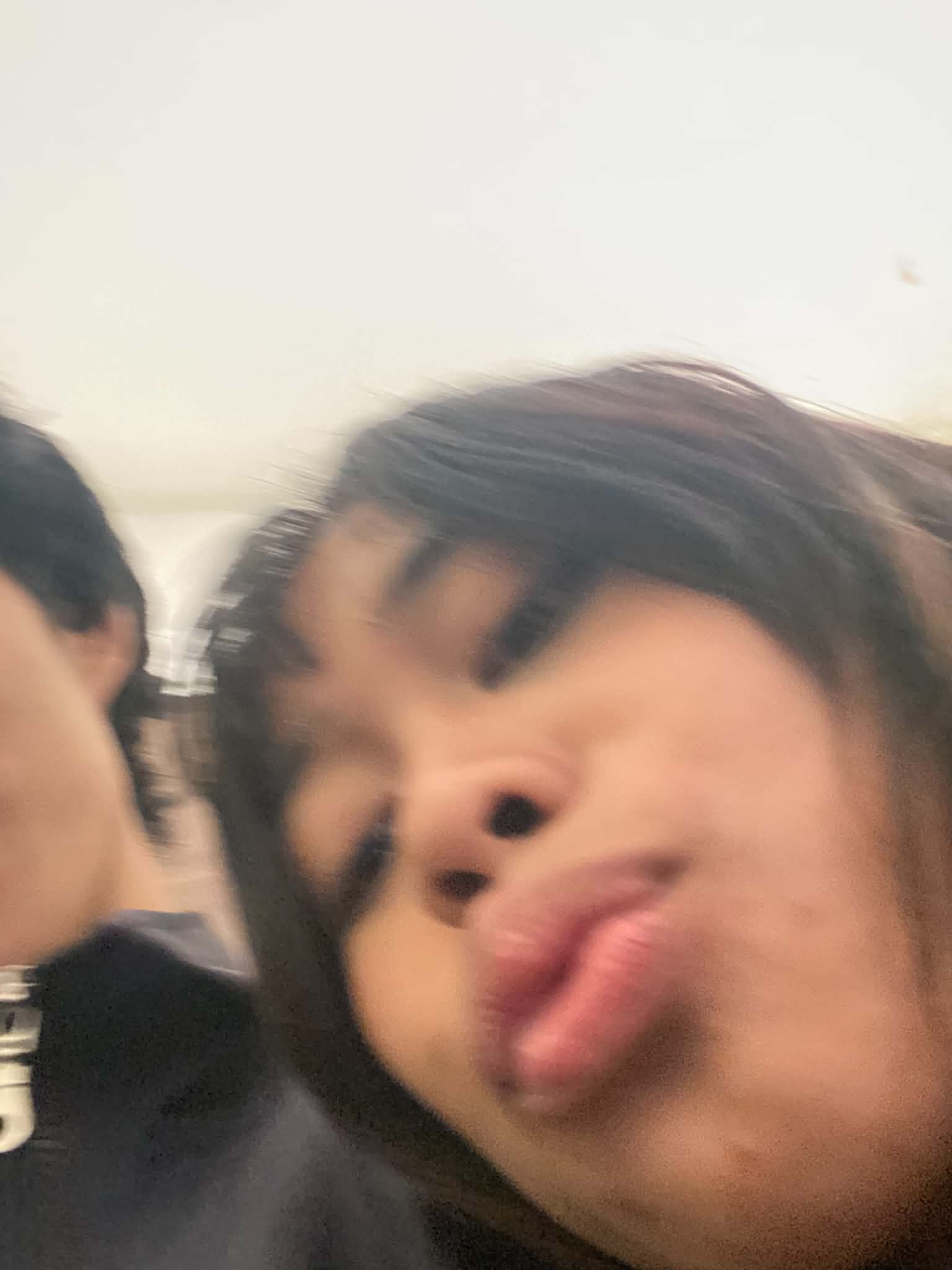 A motion-blurred close-up selfie of Jazdy making a face